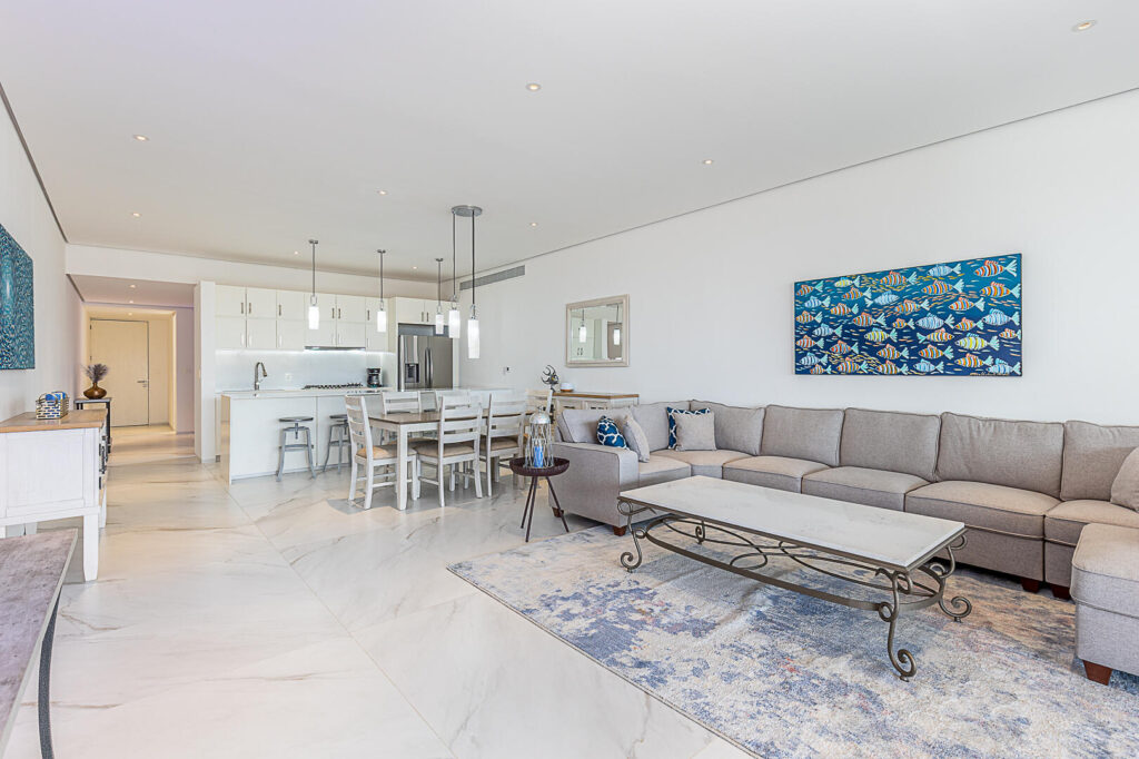 Los Cabos Cora One of the lowest-priced furnished residences currently available in Cora, this 2024-built condo is move-in ready and located within Club Campestre in San José del Cabo. The floor plan offers 3 bedrooms and 3.5 baths with approximately 1,841 sq ft of interior living space. Bright, modern interiors feature large-format tile flooring, an open-concept kitchen with island seating, and expansive sliding glass doors that connect seamlessly to oversized private decks. The interior design emphasizes clean lines, neutral finishes, and a cohesive open layout that connects the kitchen, dining, and living areas into a single, light-filled space. The kitchen is centered around a large island with quartz-style surfaces, modern cabinetry, and pendant lighting, opening directly to the main living area for easy entertaining. Floor-to-ceiling sliding glass doors extend the living space outdoors, creating a strong indoor-outdoor connection and allowing natural light to flow throughout the residence.Living and dining areas are furnished with contemporary pieces scaled appropriately for the space, complementing the modern architectural style seen throughout the development. Bedrooms are well-proportioned and designed for privacy, while bathrooms feature glass-enclosed showers and streamlined finishes consistent with the home's overall aesthetic. Privacy blinds, LED televisions with integrated switching, and thoughtfully placed lighting add functionality while maintaining a clean visual profile.Outdoor living areas are a standout feature, with expansive decks and patios offering generous space for seating, dining, and relaxation while overlooking the community's architectural landscaping and surrounding natural terrain.. Two covered on-property parking spaces include electricity and water connections suitable for electric vehicle charging or vehicle washing, and a private 10x10x14 storage locker with electricity provides secure owner storage.Cora is a gated, master-planned community within Campestre San José, featuring contemporary architecture and resort-style amenities visible throughout the property. Community offerings include a large swimming pool with integrated lounging areas, a hot tub, fitness center, indoor children's play area, and an enclosed dog park, all supported by 24/7 security. The Campestre San José golf course is approximately 0.5 miles away, and the private beach club on the Sea of Cortez is roughly 2.5 miles from the residence, subject to membership terms.Dining, recreation, and services are easily accessible, with Flora Farms approximately 2.8 miles away, Acre Restaurant about 3.0 miles, and the Historic Art District of downtown San José del Cabo roughly 4.5 miles from the property. Beachfront dining along the Tourist Corridor, including venues such as Veleros Beach Club and 7 Seas Grille & Seafood, is approximately 6.5 miles away, while Los Cabos International Airport is about 10.5 miles from the residence.Offered fully furnished and... – Cora Sunrise, San Jose del Cabo, San Jose del Cabo, BS